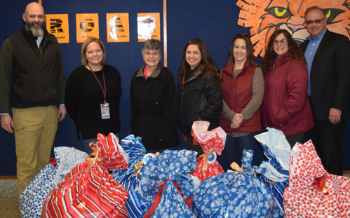 United Trust Bank employees and school officials stand with bags of coat donations